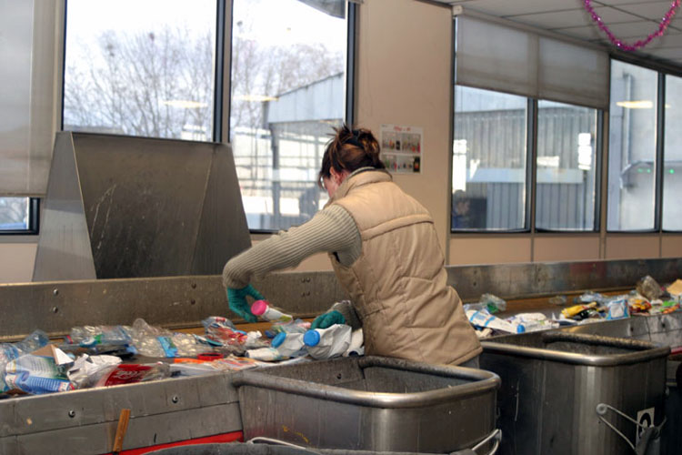 Opératrice au travail dans un centre de tri des déchets manuel.
